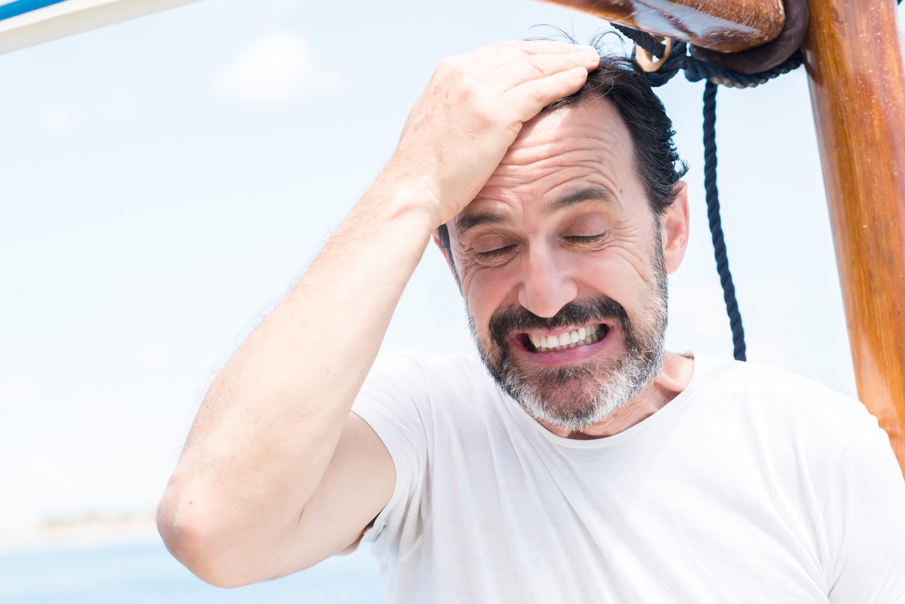 Frustrated sailor holding his head aboard a sailboat
