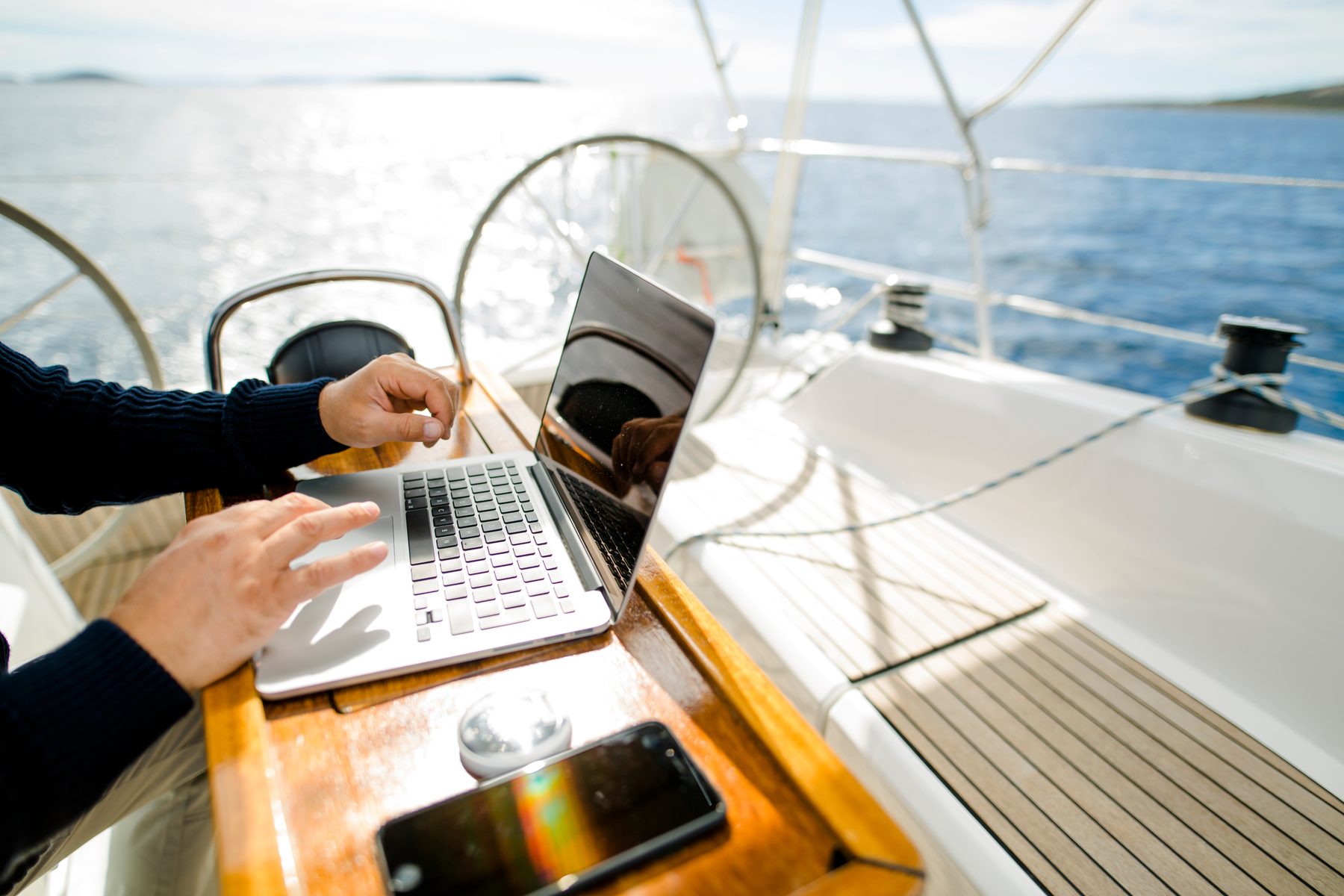 Sailor updating a logbook on a laptop in the cockpit